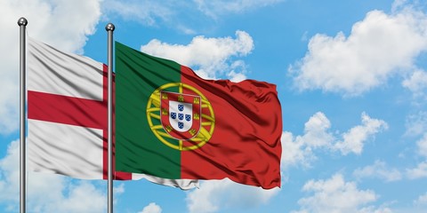 England and Portugal flag waving in the wind against white cloudy blue sky together. Diplomacy concept, international relations.
