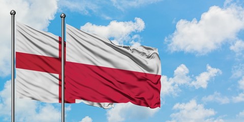 England and Poland flag waving in the wind against white cloudy blue sky together. Diplomacy concept, international relations.