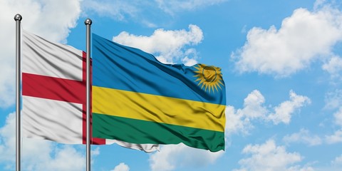 England and Rwanda flag waving in the wind against white cloudy blue sky together. Diplomacy...