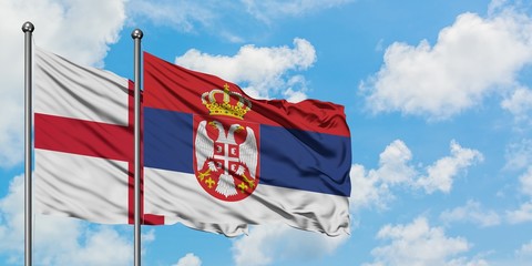 England and Serbia flag waving in the wind against white cloudy blue sky together. Diplomacy concept, international relations.