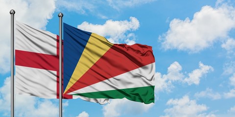 England and Seychelles flag waving in the wind against white cloudy blue sky together. Diplomacy...