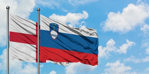 England and Slovenia flag waving in the wind against white cloudy blue sky together. Diplomacy concept, international relations.
