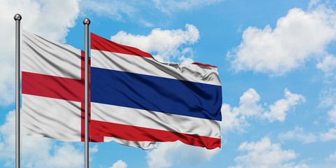 England and Thailand flag waving in the wind against white cloudy blue sky together. Diplomacy concept, international relations.