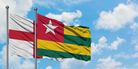 England and Togo flag waving in the wind against white cloudy blue sky together. Diplomacy concept, international relations.