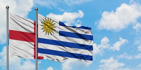 England and Uruguay flag waving in the wind against white cloudy blue sky together. Diplomacy concept, international relations.