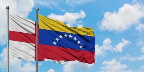 England and Venezuela flag waving in the wind against white cloudy blue sky together. Diplomacy concept, international relations.