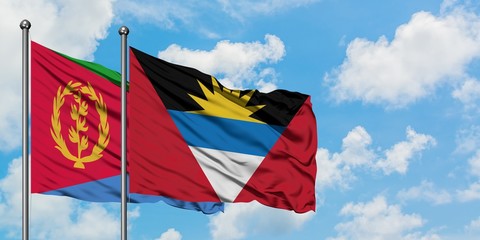 Eritrea and Antigua and Barbuda flag waving in the wind against white cloudy blue sky together. Diplomacy concept, international relations.