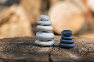 White black stone cairns, poise light pebbles on wood stump in front of brown natural background,...