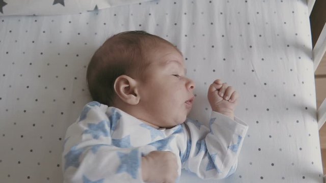 Happy young family - cute newborn baby in swinging cradle. Happy family concept. Slowmotion video.