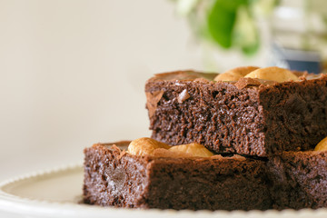 Dark chocolate fudge brownies topping with cashew nuts on white plate with copy space. Delicious taste bitter sweet, chewy and fudgy. Brownie is one type of chocolate cake. Homemade bakery concept