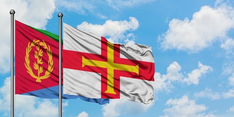 Eritrea and Guernsey flag waving in the wind against white cloudy blue sky together. Diplomacy concept, international relations.
