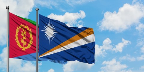 Eritrea and Marshall Islands flag waving in the wind against white cloudy blue sky together. Diplomacy concept, international relations.