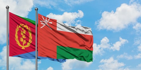 Eritrea and Oman flag waving in the wind against white cloudy blue sky together. Diplomacy concept, international relations.