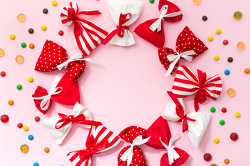 Christmas background with gift bags, candies and copy space. Pink background with red  and white presents. Flat lay