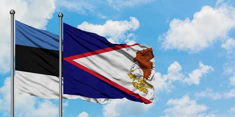 Estonia and American Samoa flag waving in the wind against white cloudy blue sky together....