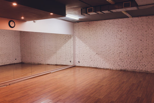 Interior of an empty dance and fitness studio with loft design and big mirrors.