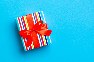 Fototapeta premium Gift box with red bow for Christmas or New Year day on blue background, top view with copy space