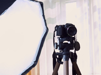 Photo camera on a tripod and white background.