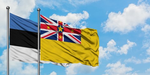 Estonia and Niue flag waving in the wind against white cloudy blue sky together. Diplomacy concept, international relations.