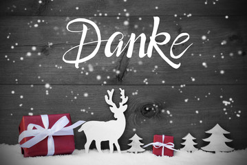 German Calligraphy Danke Means Thank You. Red Christmas Decoration Like Tree, Gift, And Reindeer. Black Wooden Background With Snowfalkes
