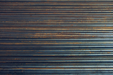 The round steel hollow wire inside, rusted, real colors, dirty, arranged in an orderly manner in the same plane and partial light. Background.Taken at outdoor warehouse in the construction site