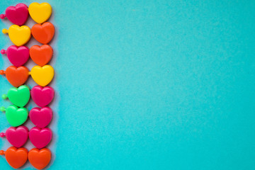 Colourful pairs of plastic hearts on left side on a blue background. Relationships. Yellow, pink, green, orange hearts. 