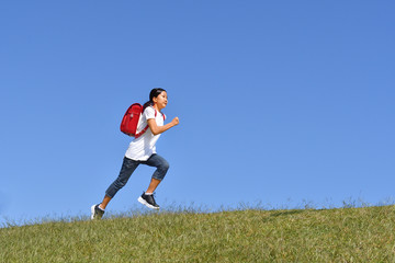 Fototapeta na wymiar 青空で走る小学生の女の子（ランドセル）