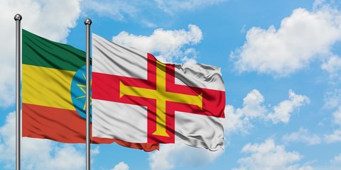 Ethiopia and Guernsey flag waving in the wind against white cloudy blue sky together. Diplomacy concept, international relations.