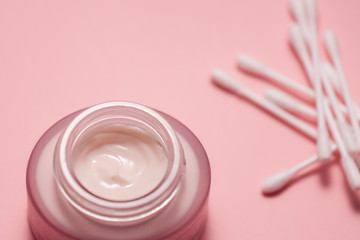Cosmetic cream in a can and cotton swabs on a pink background 