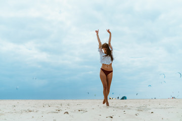 girl on the beach stretches standing with her back to the sea