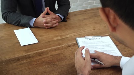 Businessman giving contract paper to his partner to sign on the table 
