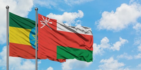 Ethiopia and Oman flag waving in the wind against white cloudy blue sky together. Diplomacy concept, international relations.