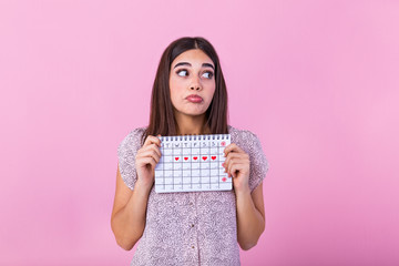 Portrait of young woman in dress, holding female periods calendar for checking menstruation days isolated on trending pink background. Medical healthcare, gynecological concept.