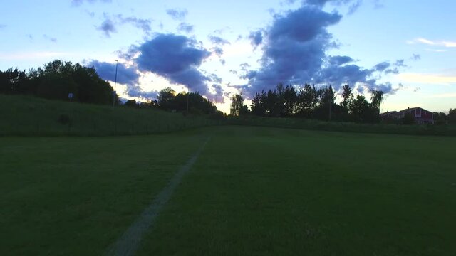 Green soccer field with cinematic sunset and beautiful clouds