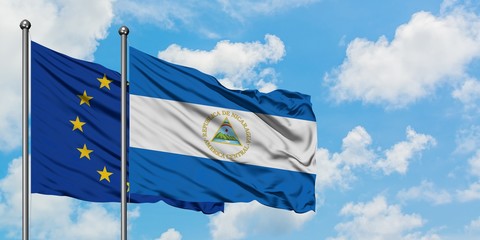 European Union and Nicaragua flag waving in the wind against white cloudy blue sky together....