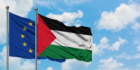 European Union and Palestine flag waving in the wind against white cloudy blue sky together....