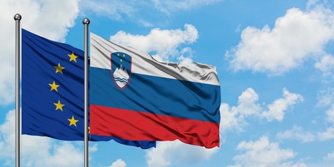 European Union and Slovenia flag waving in the wind against white cloudy blue sky together. Diplomacy concept, international relations.