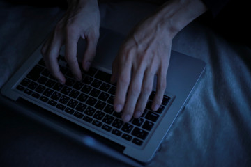 暗い中でパソコンを使う男性の手元