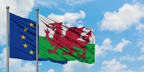European Union and Wales flag waving in the wind against white cloudy blue sky together. Diplomacy...