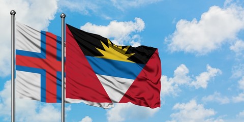 Faroe Islands and Antigua and Barbuda flag waving in the wind against white cloudy blue sky together. Diplomacy concept, international relations.