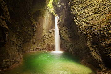 Mystical view of the rocky amphitheatre with a green pool and a white beam of water. 15-metre-high...