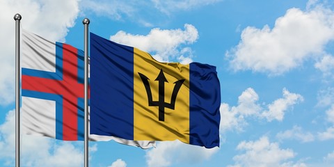 Faroe Islands and Barbados flag waving in the wind against white cloudy blue sky together. Diplomacy concept, international relations.