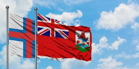 Faroe Islands and Bermuda flag waving in the wind against white cloudy blue sky together. Diplomacy...