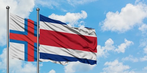 Faroe Islands and Costa Rica flag waving in the wind against white cloudy blue sky together. Diplomacy concept, international relations.