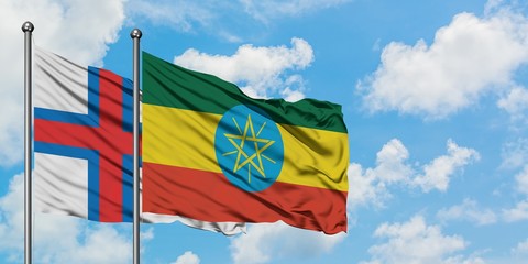 Faroe Islands and Ethiopia flag waving in the wind against white cloudy blue sky together. Diplomacy concept, international relations.