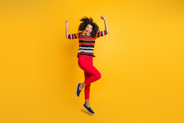 Fototapeta na wymiar Omg sales. Full length photo of astonished crazy brunette wavy hair girl hear wonderful news win discounts jump raise fists scream wow wear red pants trousers isolated yellow color background