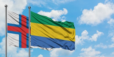 Faroe Islands and Gabon flag waving in the wind against white cloudy blue sky together. Diplomacy concept, international relations.