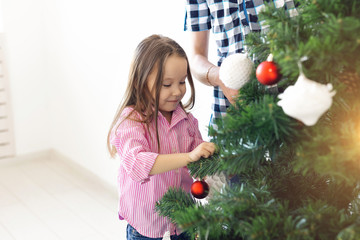 Holidays, parents and celebrating concept - Happy family decorating a Christmas tree with baubles in the living-room on white background