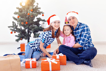 X-mas and holiday concept - Family opening christmas present in front of tree