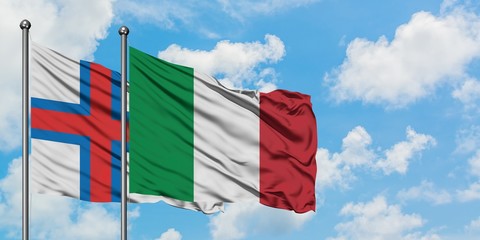 Faroe Islands and Italy flag waving in the wind against white cloudy blue sky together. Diplomacy concept, international relations.